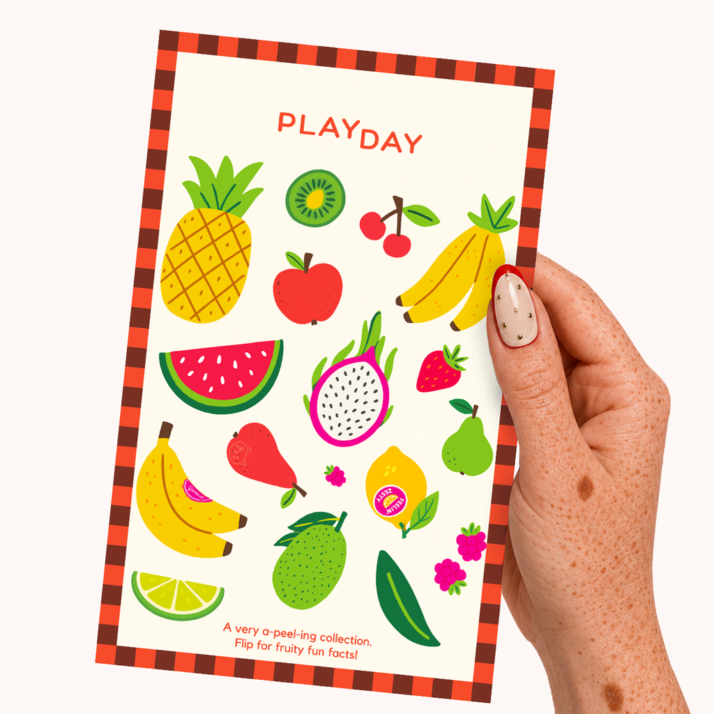 A hand holds a stickersheet featuring colorful fruit illustration stickers and the title 'PLAYDAY' on a cream background with a red-and-orange plaid border.