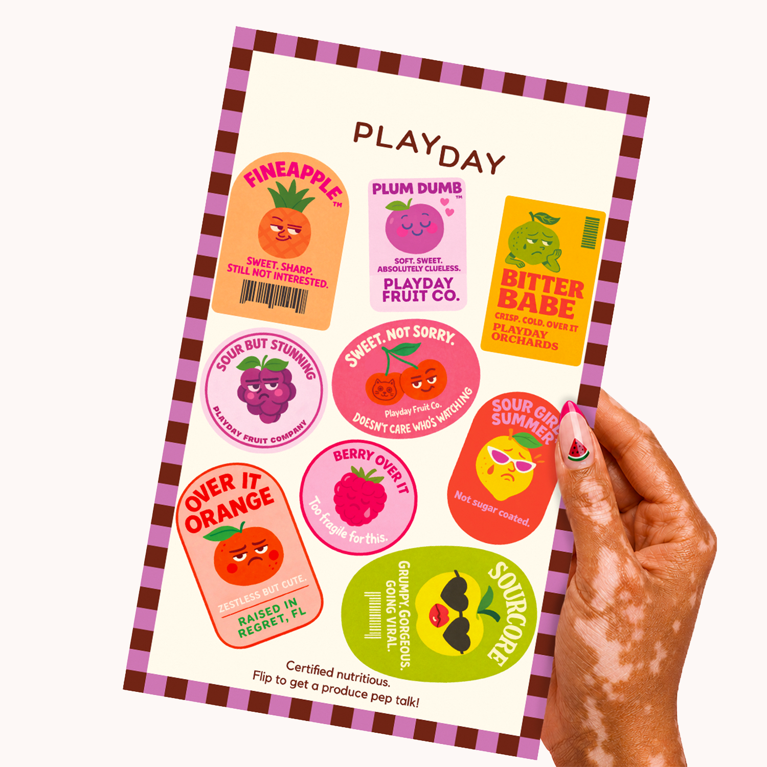 A hand holds a Playday sticker sheet featuring colorful fruit-themed stickers like Pineapple, Plum Dumb, and Bitter Babe on a cream background with a pink checkered border.