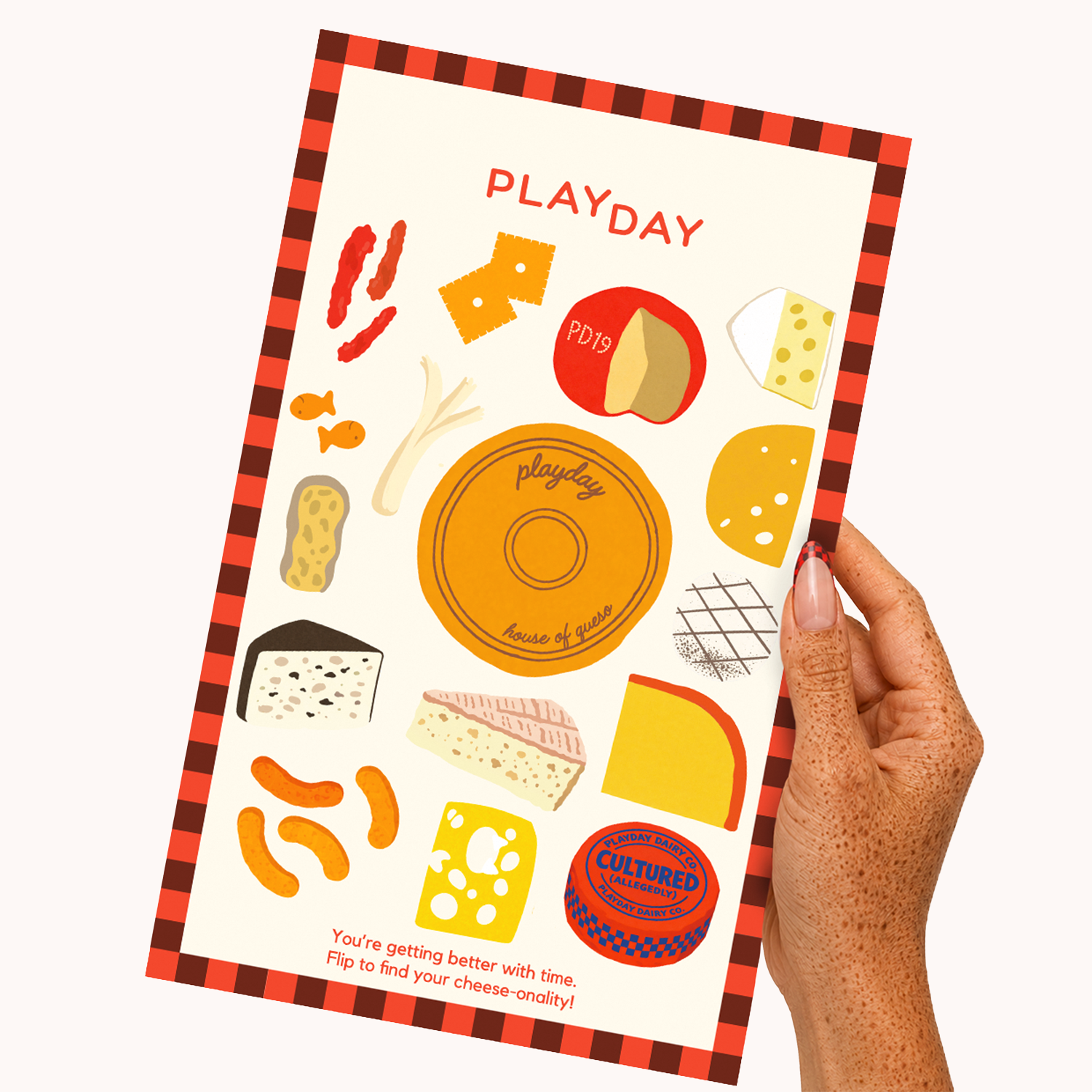 A hand holds a Playday cheese-themed sticker sheet featuring illustrated cheese wedges, cheese curds, chili peppers, and a round cheese grater. The sheet has a red and black plaid border and the text 'PLAYDAY' at the top.